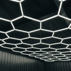 Large 46-grid dimmable interconnected white LED hexagon ceiling lighting array illuminating garage with dark walls